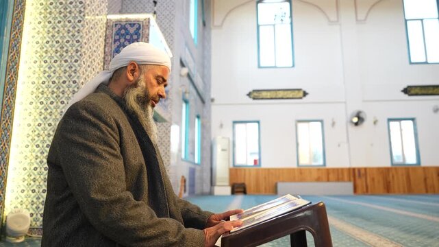 A Muslim sheikh reading the Qur&rsquo;an in the mihrab of the mosque, an elderly Muslim man praying during Ramadan. Concept of religions, Eid al-Fitr.