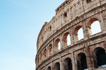 Fototapeta premium Historic Roman Colosseum stands tall under blue sky in Rome, Italy during the day