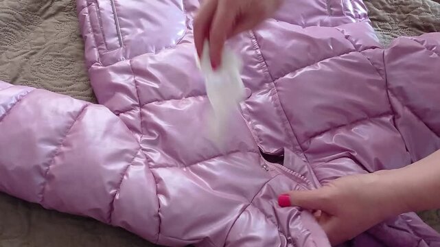 Stock video of how to wet wipe a winter purple warm children's jacket with a damp cloth