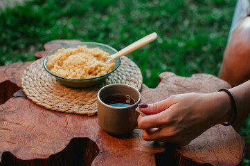 mano sosteniendo taza de mate cocido con un buen plato de reviro al fondo, desayuno casero © Daniel