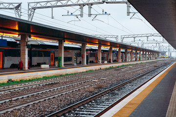 Train station platform with empty tracks and waiting area in a city during the day