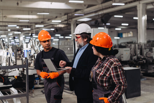Factory manager showing laptop information to diverse workers