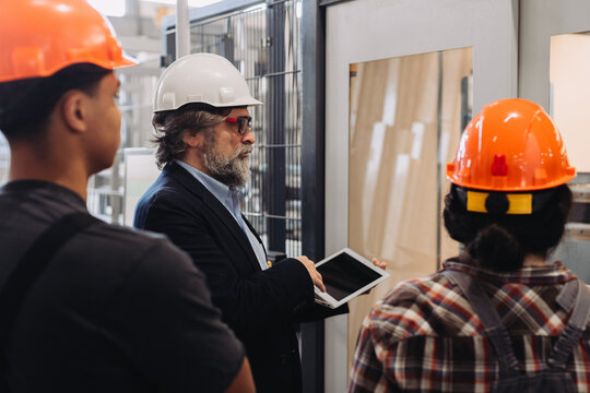 Factory manager discussing window production with workers