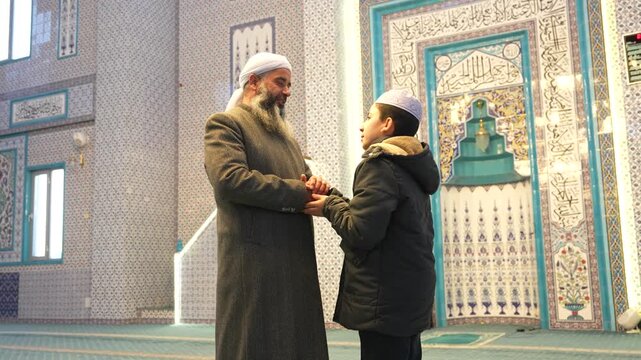 A Muslim sheikh hugging children in a mosque and congratulating them on the occasion of Eid al-Fitr. Islamic holidays. Muslims celebrating Eid al-Fitr after the end of the month of Ramadan.