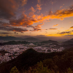 Panoramic sunset view of Nha Trang city from an Angel mountain viewpoint. Scenic coastline with mountains, urban buildings and soft clouds in the evening sky. Tropical landscape of Vietnam travel