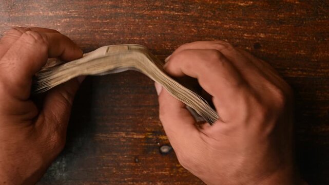 Top View of Man Placing 500 Rupee Note Bundles on Wooden Table &ndash; Financial Concept