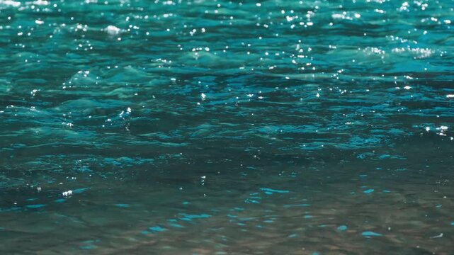 Sparkling Turquoise River Water Surface with Sunlight Reflections