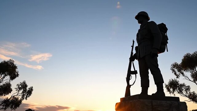 Silhouette of a soldier statue with a rifle on a pedestal at sunset