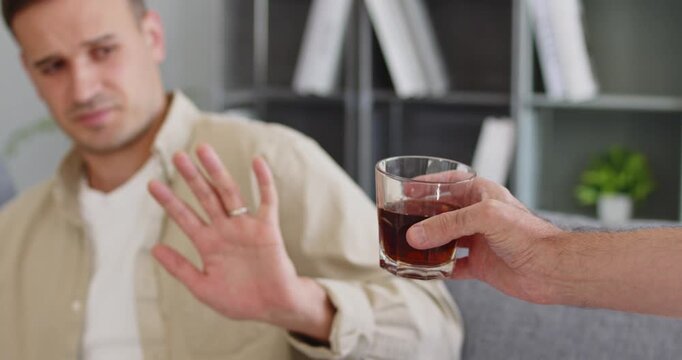 Man shows refusal gesture to alcohol temptation. Symbolizes sobriety and recovery from addiction, highlighting willpower, support, and prevention. Clear message about choosing sobriety.