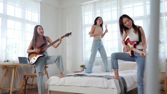 Asian female friends playing music band together at home