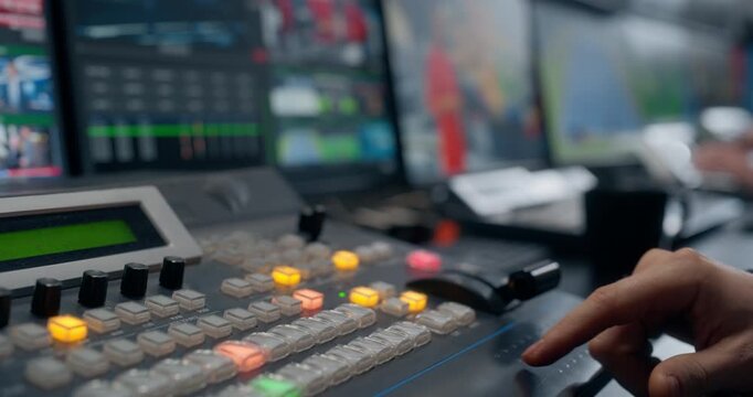 TV Station Production Control Room. Operator Switching Live Feeds, Pressing Control Panel Buttons, Coordinating Broadcast Output for News or Studio Programming. Close-up Focus on Hands and Buttons