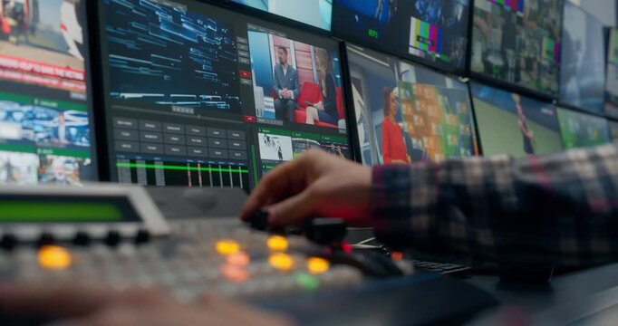 TV Station Control Room. Operators Cueing Sources, Adjusting Switcher Controls, Tracking Monitors, Managing Live News, Weather, Sports Feeds Broadcast. Focus on Screens and Hands Pushing Buttons
