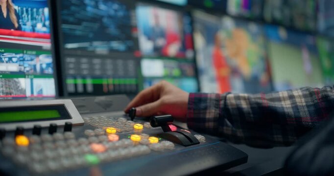 TV Station Control Room. Operators Cueing Sources, Adjusting Switcher Controls, Tracking Monitors, Managing Live News, Weather, Sports Feeds Broadcast. Focus on Screens and Hands Pushing Buttons