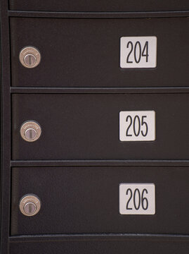 close up of postal  boxes with numbers 204 205 and 206 consecutively numbered three mailboxes stacked on top of each other with lock beside  numbers