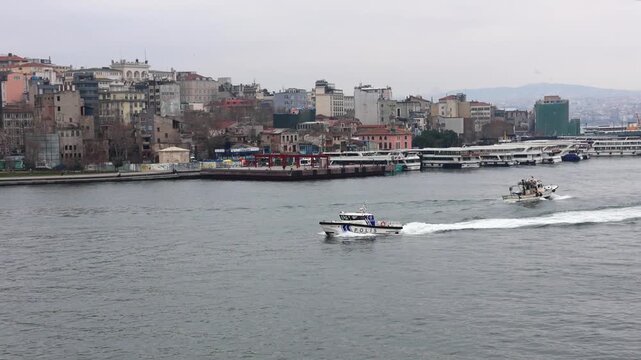 Police patrol boat speeding on the Bosphorus with Istanbul skyline background.