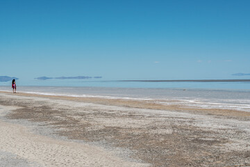 Obraz premium A woman is walking on a beach with a clear blue sky above her