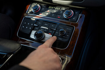 Driver finger pressing tune button on car multimedia control panel to adjust audio settings such as balance, fader, bass and treble.