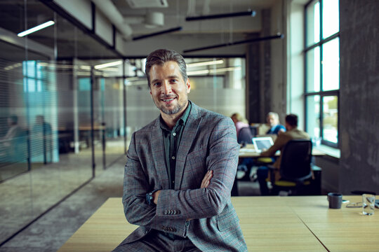Confident business leader posing in modern office with team
