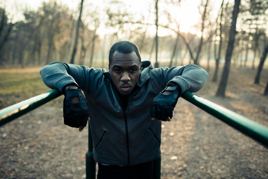 Man resting on parallel bars in outdoor park