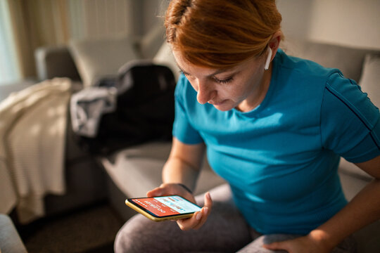 Woman checking fitness app on smartphone at home