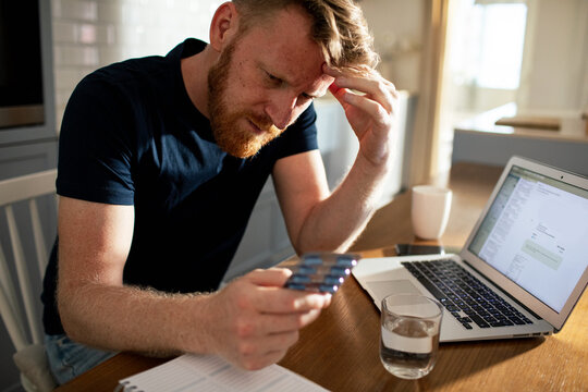 Stressed man checking medication at home office
