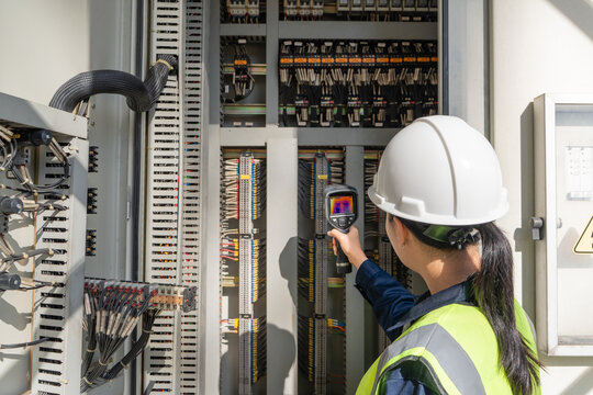 Engineer performs predictive maintenance with a thermal camera inside an electrical control cabinet, detecting heat anomalies to improve safety, reliability, and fault analysis.