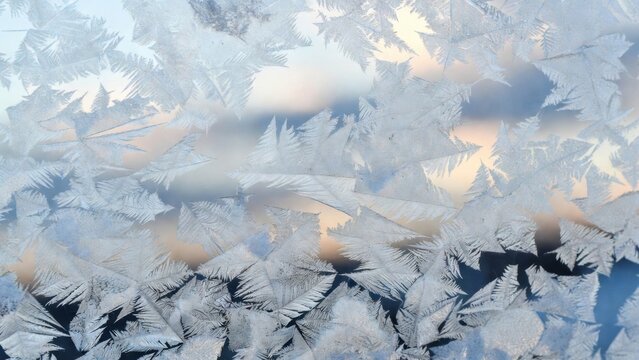 Window frost crystals covering glass with blurred sunrise background