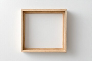 Overhead view of a square, wooden frame on a plain, white wall, casting a soft shadow