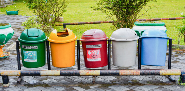 Rows of plastic trash cans in green, yellow, red, grey, and blue for environmental waste management. 