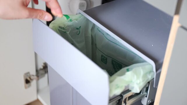 A housewife throwing a used paper napkin into a garbage bin in kitchen. Waste separation concept