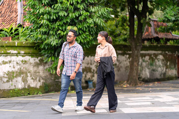 Obraz premium Asian Couple Walking Together on City Street with Green Trees