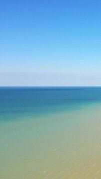 Tranquil view of clear blue sky meeting the calm, turquoise waters at Juno Beach in Bernieres-sur-Mer, Normandy. Peaceful seascape with gentle waves and serene atmosphere.