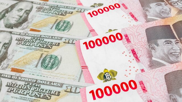 Scattered of 100 America dollar bill and 100 Indonesian Rupiah. Concept of world currency exchange