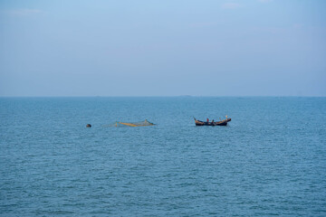 Fishermen working on boat pulling fishing net in ocean