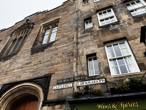 Historic Royal Mile street signs on Castlehill and Lawnmarket with stone facade and Wines and Spirits shopfront in Edinburgh, Scotland, UK
