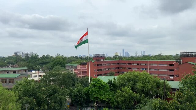 Indian Tri Colour National Flag Fluttering in front of Delhi school's building, shot from different angle and panning.