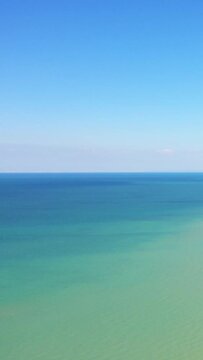 Calm turquoise waters and clear blue sky create a serene seascape at Juno Beach, Bernieres-sur-Mer, France. Peaceful and minimalistic coastal scene ideal for backgrounds or relaxation themes.