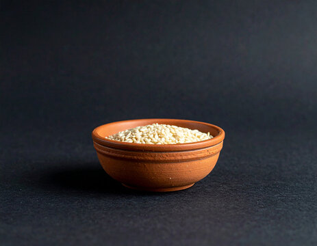 Peque&ntilde;o cuenco de barro con semillas en zona inferior sobre fondo negro con espacio negativo