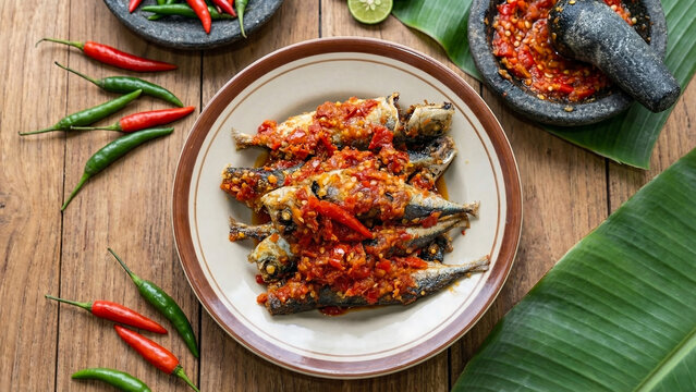 High-quality food photography of spicy fried fish with sambal. Savory Southeast Asian cuisine on a rustic wooden table. Ideal for restaurant menus, food delivery banners, and culinary ads.
