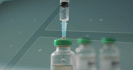 Withdrawing medication from glass vial with green cap at lab bench, showing droplet on syringe tip