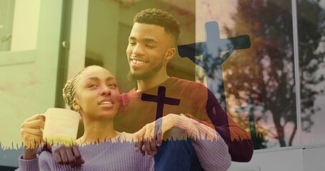 Sitting couple wearing knit sweaters holding mug on front steps, showing three cross silhouettes