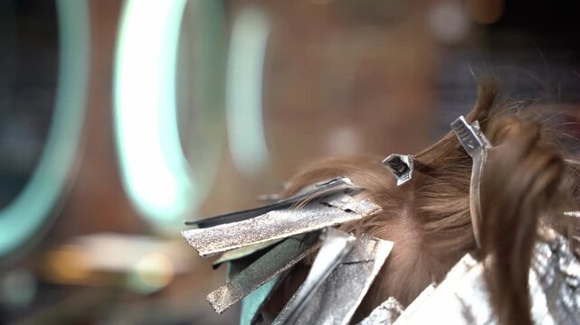 Professional hair stylist using a tail comb to section hair for a foil highlighting treatment