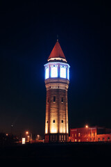 Obraz premium Illuminated Water Tower at Night, Glowing Architectural Landmark Against a Deep Starry Sky