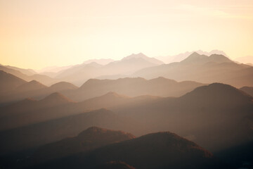 Obraz premium Sun Rays Piercing a Misty Alpine Valley at Golden Hour, Layered Mountain Ranges in Soft Morning Light with Crepuscular Rays
