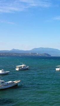 Traditional fishing boat floating on turquoise waters with distant mountains under a clear blue sky in Koroni, Greece.