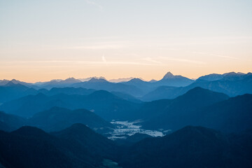 Obraz premium Sun Rays Piercing a Misty Alpine Valley at Golden Hour, Layered Mountain Ranges in Soft Morning Light with Crepuscular Rays
