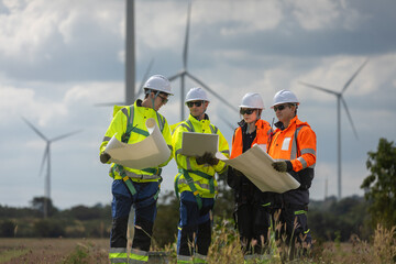 Engineer and technicians analyzing wind turbine project using blueprint at renewable energy farm...
