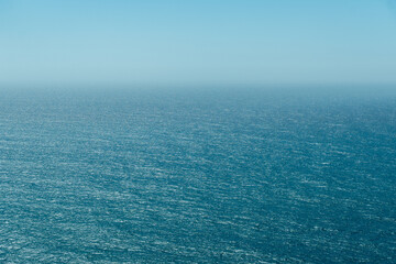 Expansive view of the Atlantic Ocean with gentle waves and a serene blue sky, captured near Lisbon. Perfect for backgrounds, travel inspiration, or relaxation themes. © Flash Vector