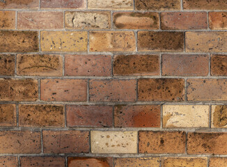Weathered red and yellow brick wall showing rough texture, mortar lines and aging stains, ideal for backgrounds, architecture projects, design mockups, marketing visuals and vintage themes © evannovostro