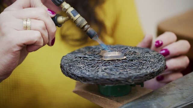 Jeweler using a blowtorch to solder a small silver piece